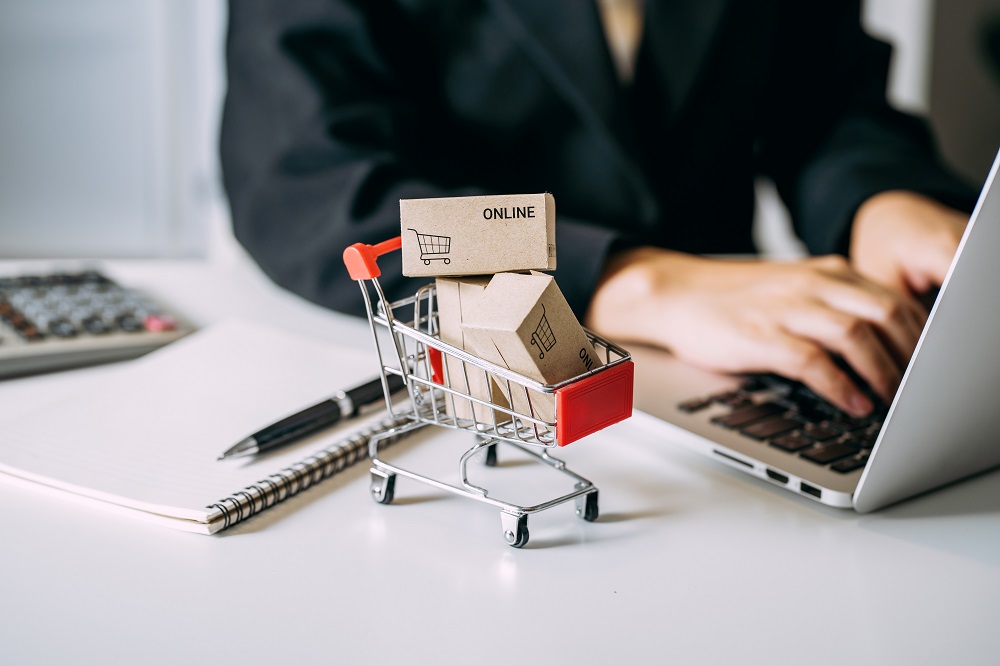 card box small in shopping cart with businesswomen using laptop on a desk, e-commerce, and delivery online business concept.